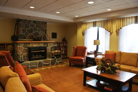 Sofas and orange armchairs around a coffee table beside a stone fireplace