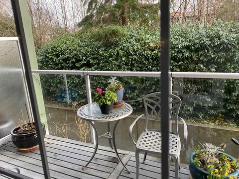 Covered suite deck with a small table, chairs and potted plants.