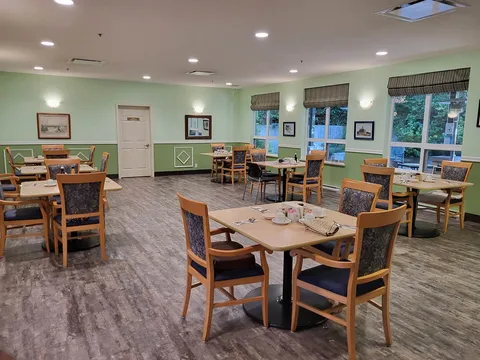 Assisted-living dining room with set tables and chairs beside windows.