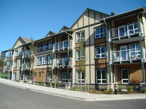 Assisted-living residence facade with balconies and gabled roof sections.
