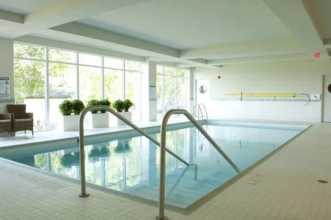 Indoor pool with steps, steel handrails, large windows and wicker chairs