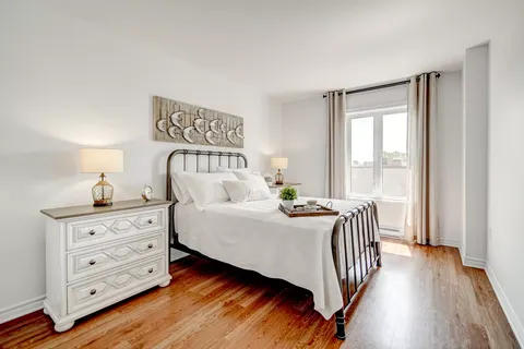 Bedroom with a metal bed frame, white dressers and a glazed balcony door