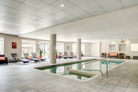 Indoor swimming pool with tiled columns, loungers and large windows