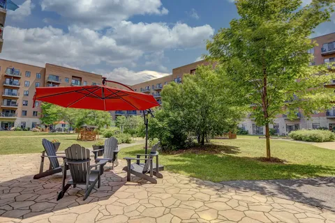 Paved courtyard with chairs, a red umbrella, lawns and trees