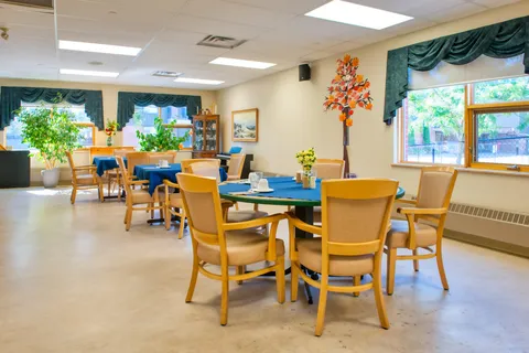 Dining room with round tables, wood chairs and large windows.
