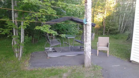 Garden seating area with a covered swing beside trees.