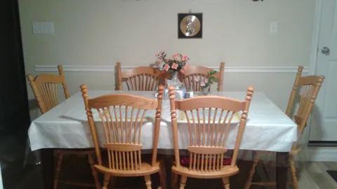 Dining table with wooden chairs and a flower arrangement.