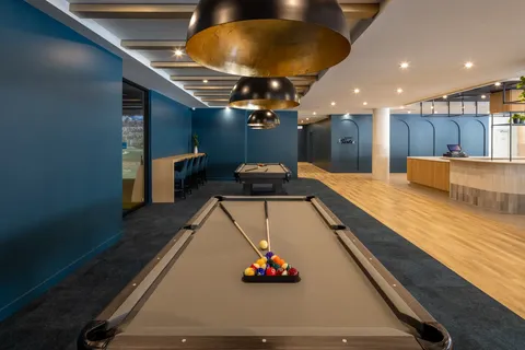 Two billiards tables beneath pendant lights beside a counter