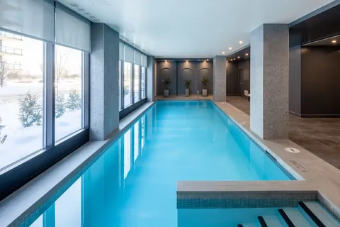 Indoor pool beside large windows and a tiled walkway
