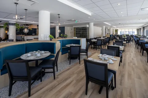 Dining room with set tables, dark chairs and blue booth seating