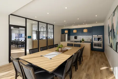 Long dining table beside a kitchen with blue cupboards