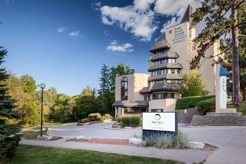 Multi-storey residence beside a driveway, steps and landscaped beds.