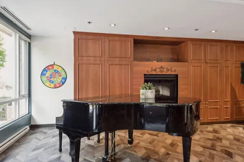 Grand piano beside a fireplace and wooden cabinets