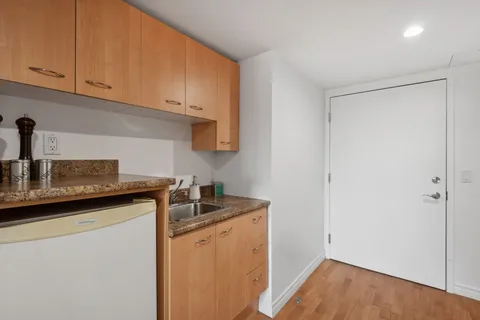 Kitchenette with wooden cabinets, a refrigerator and a sink