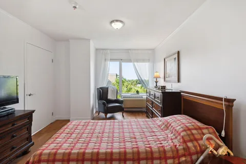 Bedroom with a bed, armchair, television and chest of drawers
