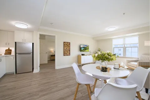 Suite living and dining area beside a white kitchen