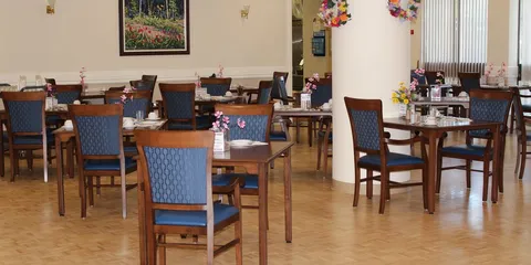 Dining room with wooden tables, blue upholstered chairs and floral centrepieces