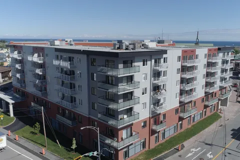 Grey and red residence with balconies, seen from above with the water beyond