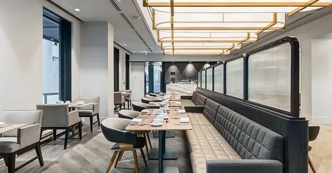 Dining room with set tables, upholstered chairs and a long banquette