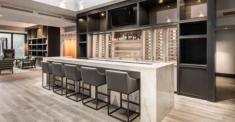 Bar counter with tall stools and shelves of bottles and glasses