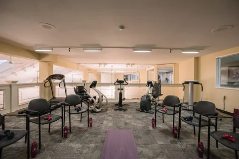 Fitness room with exercise machines, chairs and wall mirrors