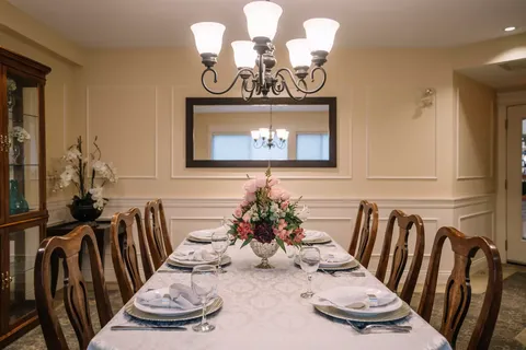 Private dining table set beneath a chandelier beside a wall mirror