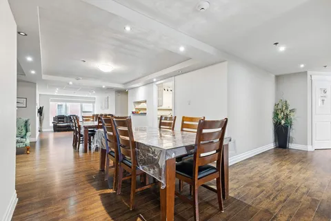 Dining area with wooden tables and chairs beside a kitchen serving opening