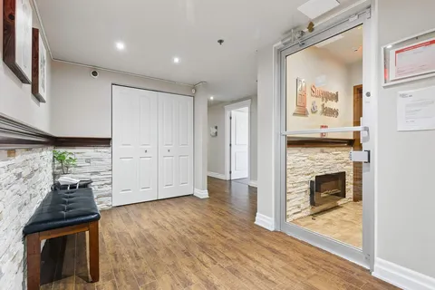 Glass entrance door beside a padded bench and stone wall