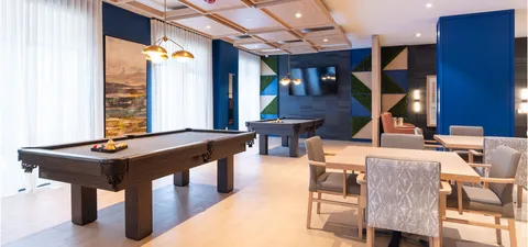 Billiards table beside tables, chairs and a large window