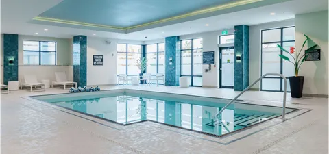 Indoor swimming pool with large windows, tiled walls and metal handrails