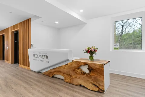 Entrance reception area with a white counter, wooden screens and a live-edge bench.