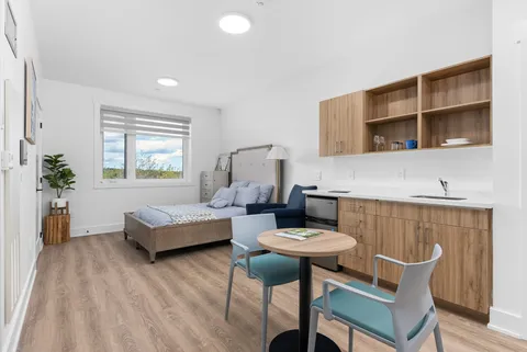 Studio suite with a bed, kitchenette, armchair and dining table.