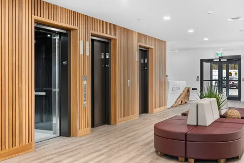Lobby corridor with wooden screens, glazed doors and seating.