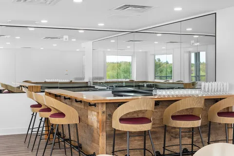 Dining and bar area with a circular table, stools and a kitchenette.