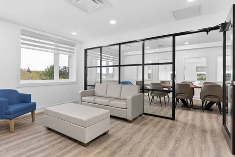 Library and sitting area with bookshelves, armchairs and large windows.