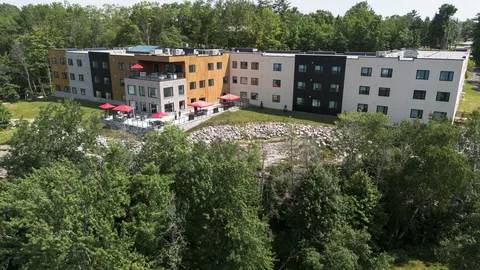 Aerial view of the residence beside woodland and exposed rock.