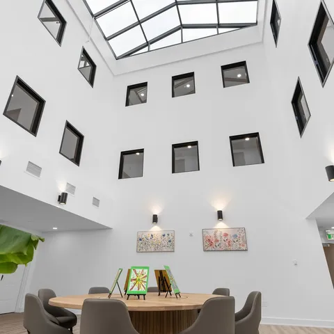 Indoor atrium with tables beneath several storeys of windows.