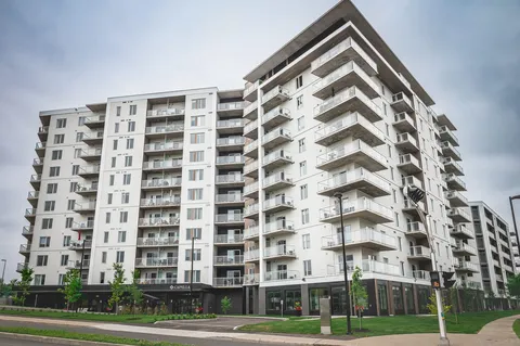 Multi-storey residence with balconies beside landscaped grounds.