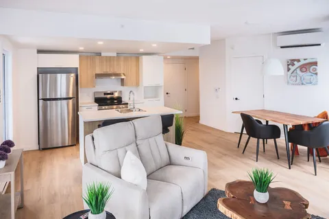 Open-plan apartment with kitchen, armchair and dining table.
