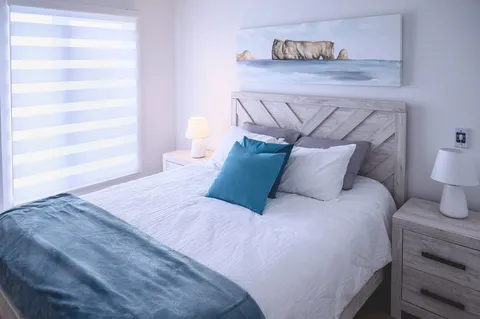 Bedroom with a double bed, window blinds and bedside table.