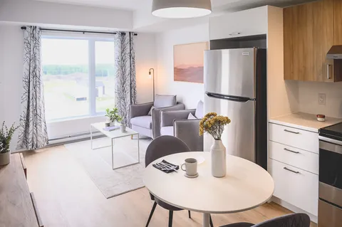 Open-plan suite with kitchen, round dining table and living area.