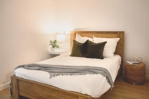 Bedroom with a double bed, bedside lamp and wicker basket.