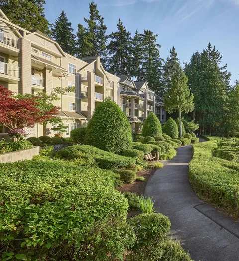 Garden path beside the residence with trimmed shrubs, benches and trees.