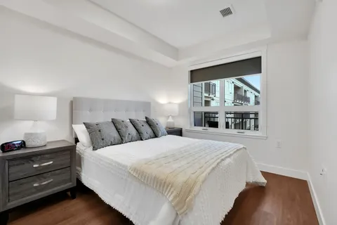 Bedroom with a white bed, bedside lamps and a window