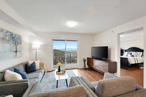 Sitting area with a sofa, armchair, television and balcony doors