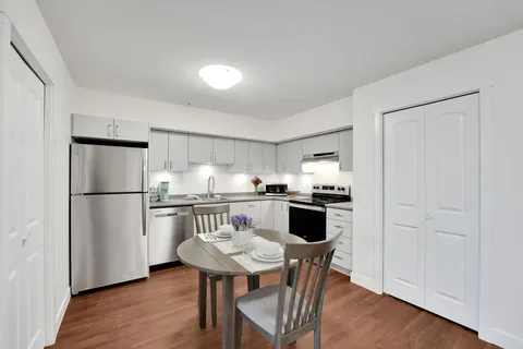White kitchen with appliances and a small dining table