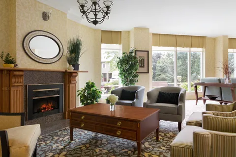 Fireside lounge with armchairs, coffee table and tall windows.