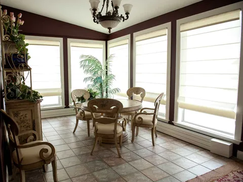 Sunroom with a round table, chairs, tiled flooring and large windows