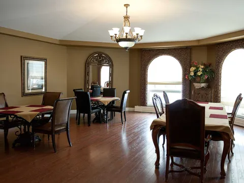 Dining room with dark chairs, tablecloths, arched windows and a chandelier