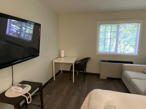 Room with a white sofa, small desk, chair and blank television